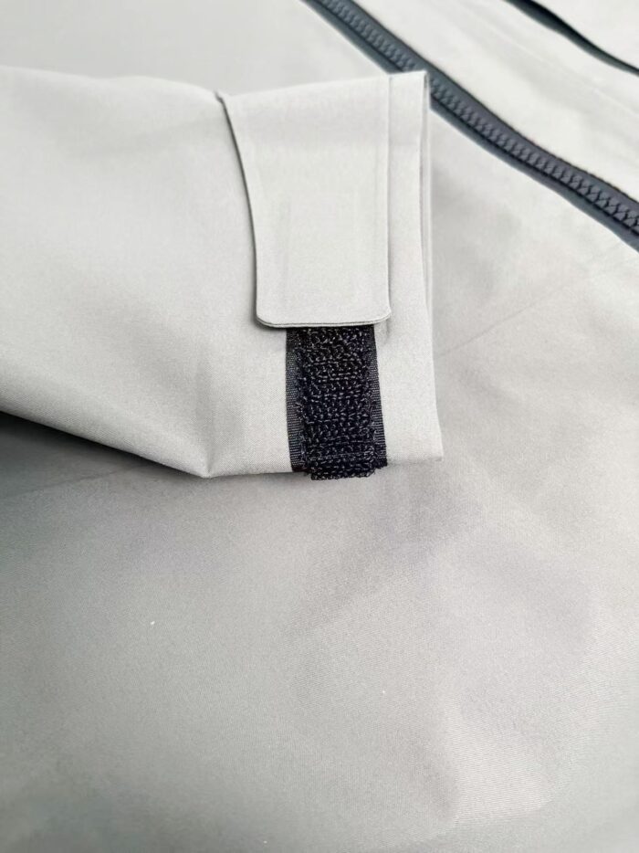Tessuto impermeabile grigio con chiusura a Velcro, ideale per abbigliamento sportivo e outdoor.