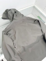 Giacca grigia impermeabile con cappuccio, ideale per outdoor e uso quotidiano.