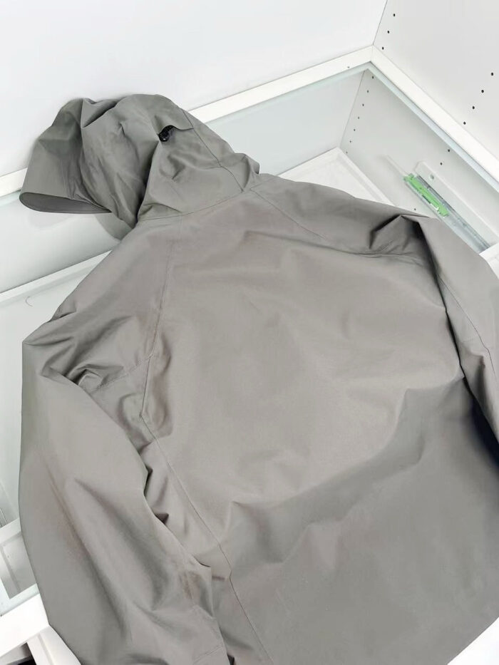 Giacca grigia impermeabile con cappuccio, ideale per outdoor e uso quotidiano.
