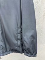 Dettaglio manica giacca grigia impermeabile con bordo elastico e motivo grafico sottile.