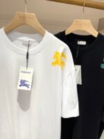 Magliette moderne bianche e nere con dettagli colorati in negozio luminoso.