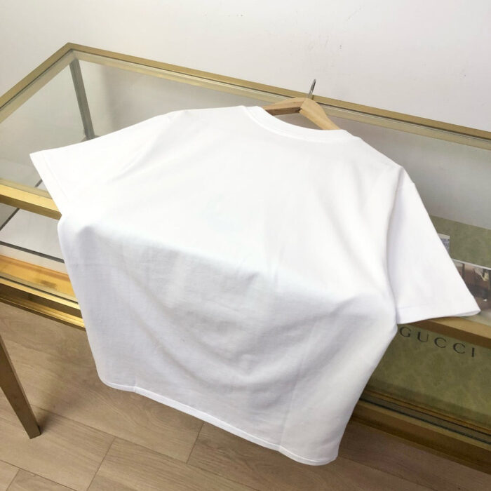 Maglietta bianca classica su tavolo di vetro con riflessi e dettagli eleganti.