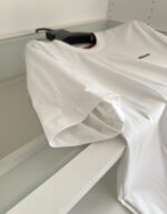Maglietta bianca casual con maniche roll-up, stile minimalista e vestibilità rilassata.