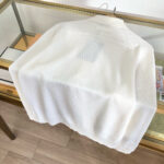 Camicia bianca moderna in esposizione su vetrina trasparente con dettagli e tessuto elegante.