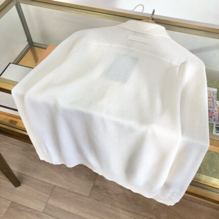 Camicia bianca moderna in esposizione su vetrina trasparente con dettagli e tessuto elegante.
