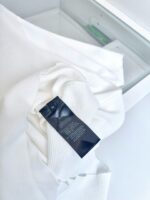 Camicia bianca con etichetta cura, stile minimalista e elegante su superficie bianca luminosa.