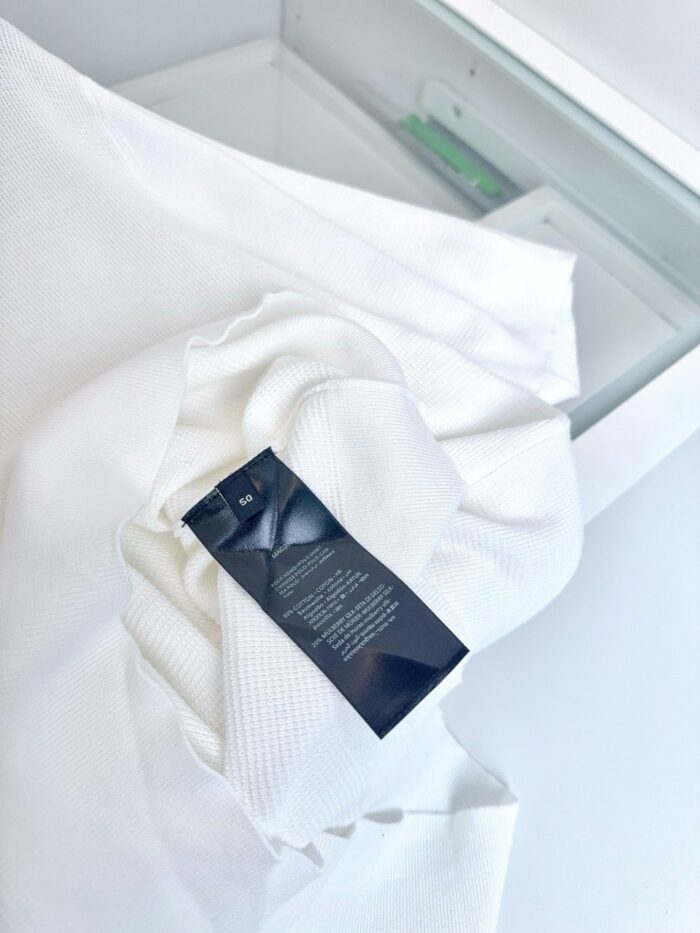 Camicia bianca con etichetta cura, stile minimalista e elegante su superficie bianca luminosa.