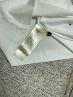 Etichetta Fendi su maglietta bianca di lusso, dettaglio moda e cura del capo.