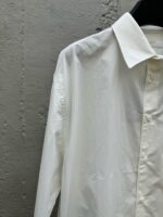 Camicia bianca classica in cotone su sfondo in cemento, stile minimalista ed elegante.