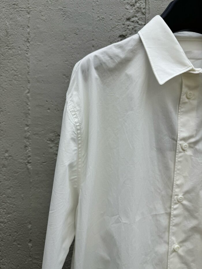 Camicia bianca classica in cotone su sfondo in cemento, stile minimalista ed elegante.