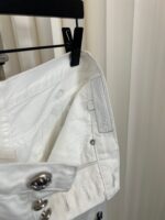 Camicia bianca in cotone con bottoni metallici, dettaglio di alta qualità e stile semplice.