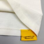 Maglietta in cotone bianco con etichetta gialla e cuciture precise, per uso quotidiano e duraturo.