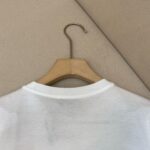Maglietta bianca in cotone su appendiabiti in legno, minimalista e di stile casual.