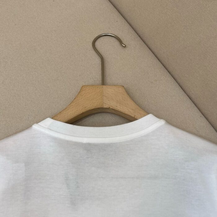 Maglietta bianca in cotone su appendiabiti in legno, minimalista e di stile casual.