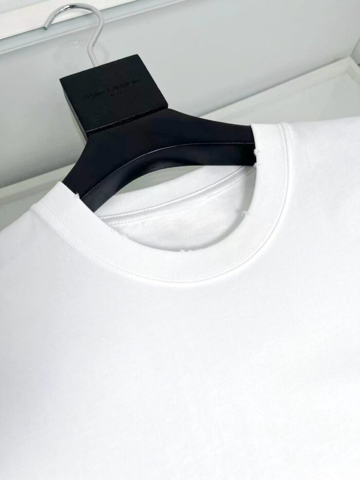 Maglietta bianca con scollo classico e gancio nero elegante, dettaglio vicino alla cucitura.