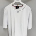 T-shirt bianca casual con logo ricamato e dettaglio colorato sul colletto, stile semplice ed elegante.