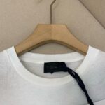Maglietta bianca a girocollo su appendiabiti in legno, minimalista ed elegante.