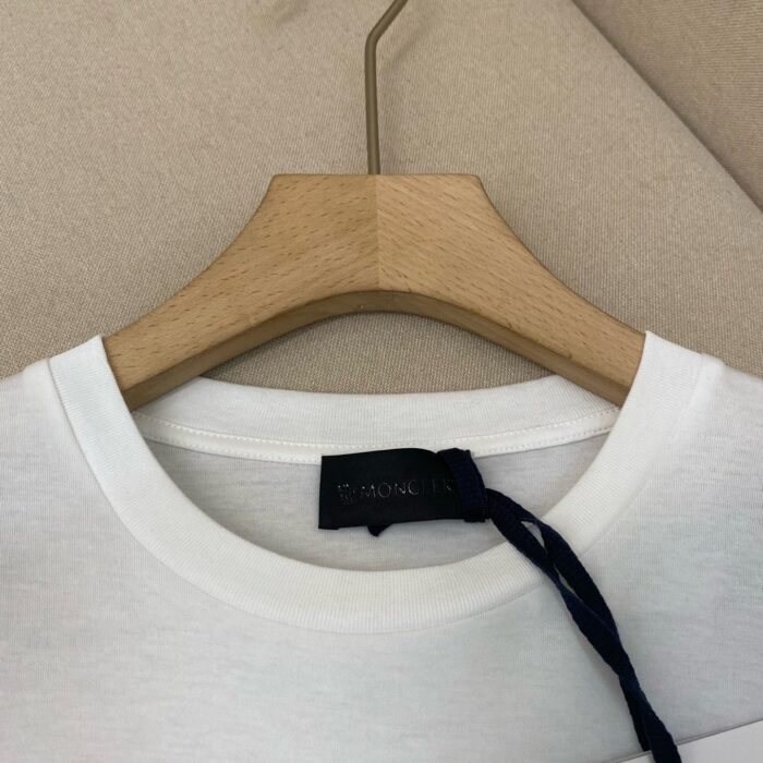 Maglietta bianca a girocollo su appendiabiti in legno, minimalista ed elegante.