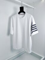 T-shirt bianco casual con dettagli di righe sulla manica, stile semplice e moderno.