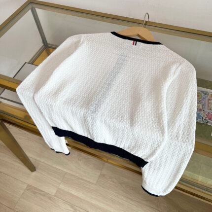 Maglione cropped bianco con dettagli neri, texture a nido dape, elegante e casual.
