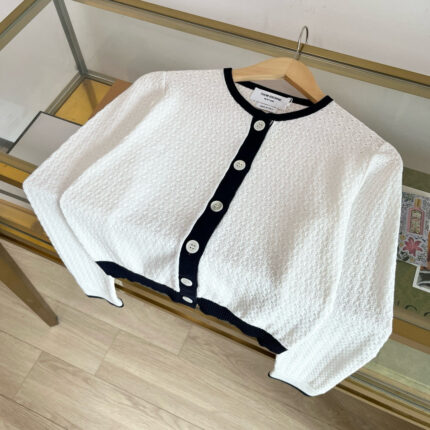 Cardigan bianco cropped con bordo nero, elegante e versatile, perfetto per ogni occasione.