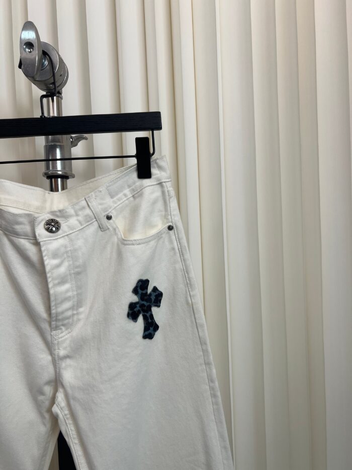 Pantaloni bianchi in denim con ricamo a croce blu navy, stile elegante e versatile.