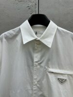 Camicia bianca elegante con logo triangolare, stile raffinato e moderno per occasioni formali.