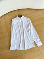 Camicia bianca elegante su pavimento in parquet a spina di pesce, stile classico e versatile.