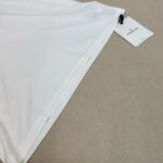 Top bianco in cotone con etichetta, drappeggio elegante e stile versatile.