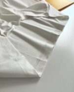Tessuto bianco morbido con cuciture sottili, perfetto per moda e decorazione minimalista.
