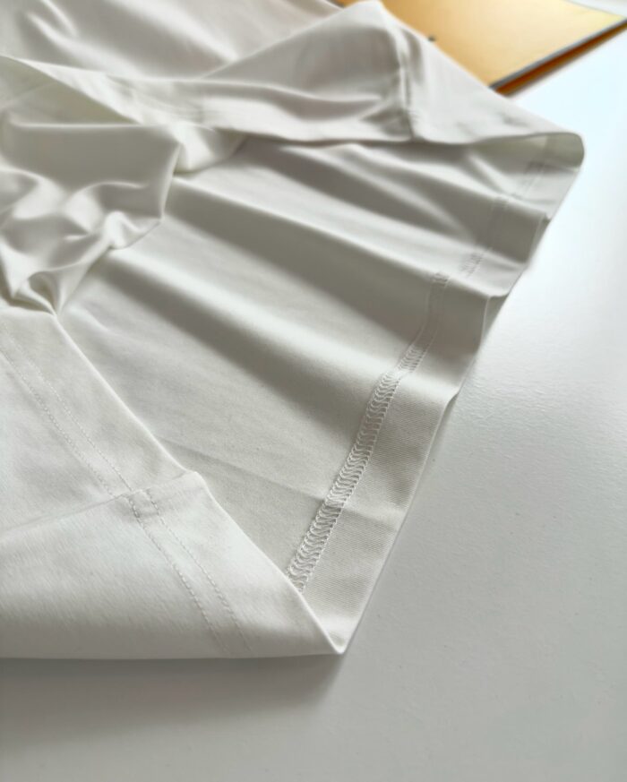 Tessuto bianco morbido con cuciture sottili, perfetto per moda e decorazione minimalista.