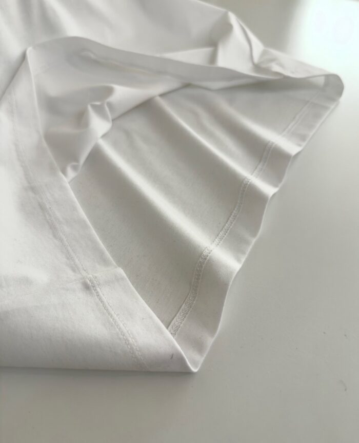 Dettaglio di tessuto bianco con cuciture precise e texture elegante, esempio di sartoria artigianale.