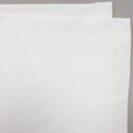 Salviette di cotone bianche eleganti su sfondo grigio, ideale per mise en place raffinate.