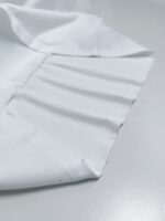 Tessuto bianco in cotone con pieghe eleganti e texture morbida, ideale per abbigliamento e interior design.