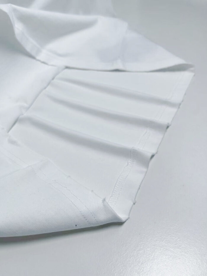 Tessuto bianco in cotone con pieghe eleganti e texture morbida, ideale per abbigliamento e interior design.