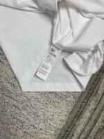 Tessuto bianco piegato con etichetta di cura su sfondo morbido e a contrasto strutturato.