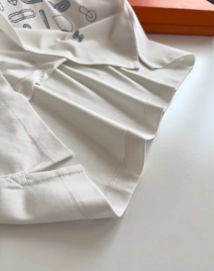 Camicia bianca piegata con dettagli interni divertenti e scatola arancione di contrasto.