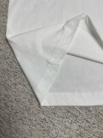 Dettaglio del bordo di una T-shirt bianca in cotone di alta qualità.