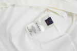 Etichetta del vestito bianco con istruzioni di cura e logo del brand.