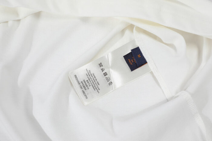 Etichetta del vestito bianco con istruzioni di cura e logo del brand.