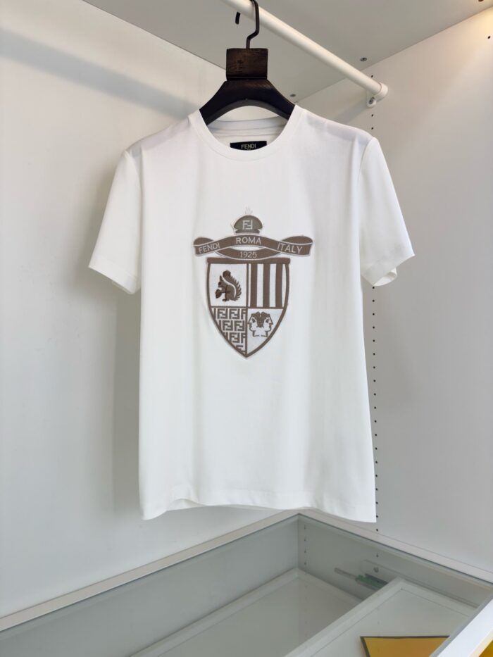 Maglietta bianca con emblem heraldico elegante e stile casual, ideale per ogni occasione.