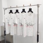 T-shirt bianche con grafica artistica e schizzi di colore, setup minimalista e moderno.