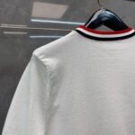 Maglia bianca con collo a costine nero e rosso, stile moderno e chic.