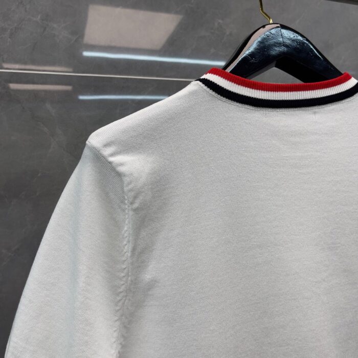 Maglia bianca con collo a costine nero e rosso, stile moderno e chic.