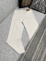 Pantaloni bianchi casual su divano moderno, con tasche e cuciture delicate per uno stile versatile.