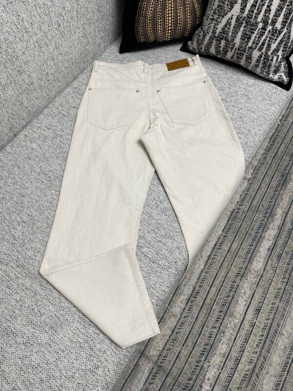 Pantaloni bianchi casual su divano moderno, con tasche e cuciture delicate per uno stile versatile.