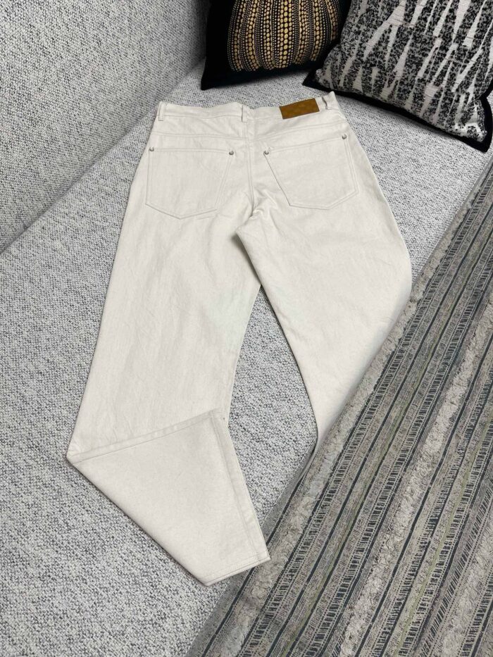 Pantaloni bianchi casual su divano moderno, con tasche e cuciture delicate per uno stile versatile.