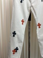 Jeans bianchi slim fit con croci blu e rosso, look moderno e di tendenza.