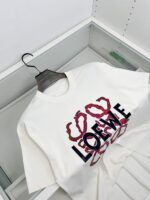T-Shirt Loewe bianco con logo nero e dettagli artistici rossi, stile minimalista e moderno.