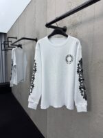 Camicia bianca a maniche lunghe con dettagli floreali neri, stile minimalista e moderno.